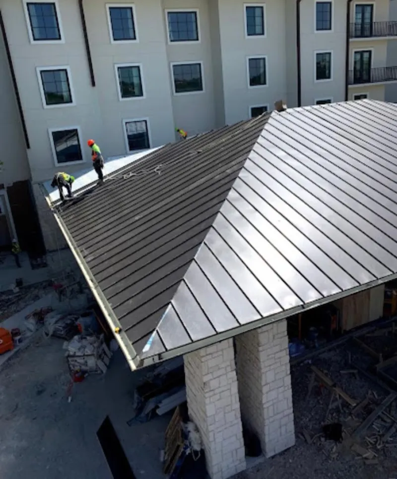 Crew installing standing seam metal roof panels on a commercial project in San Leon